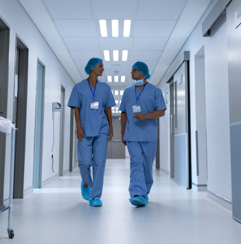 Front view of diverse surgeons talking with each other while walking in the corridor at hospital